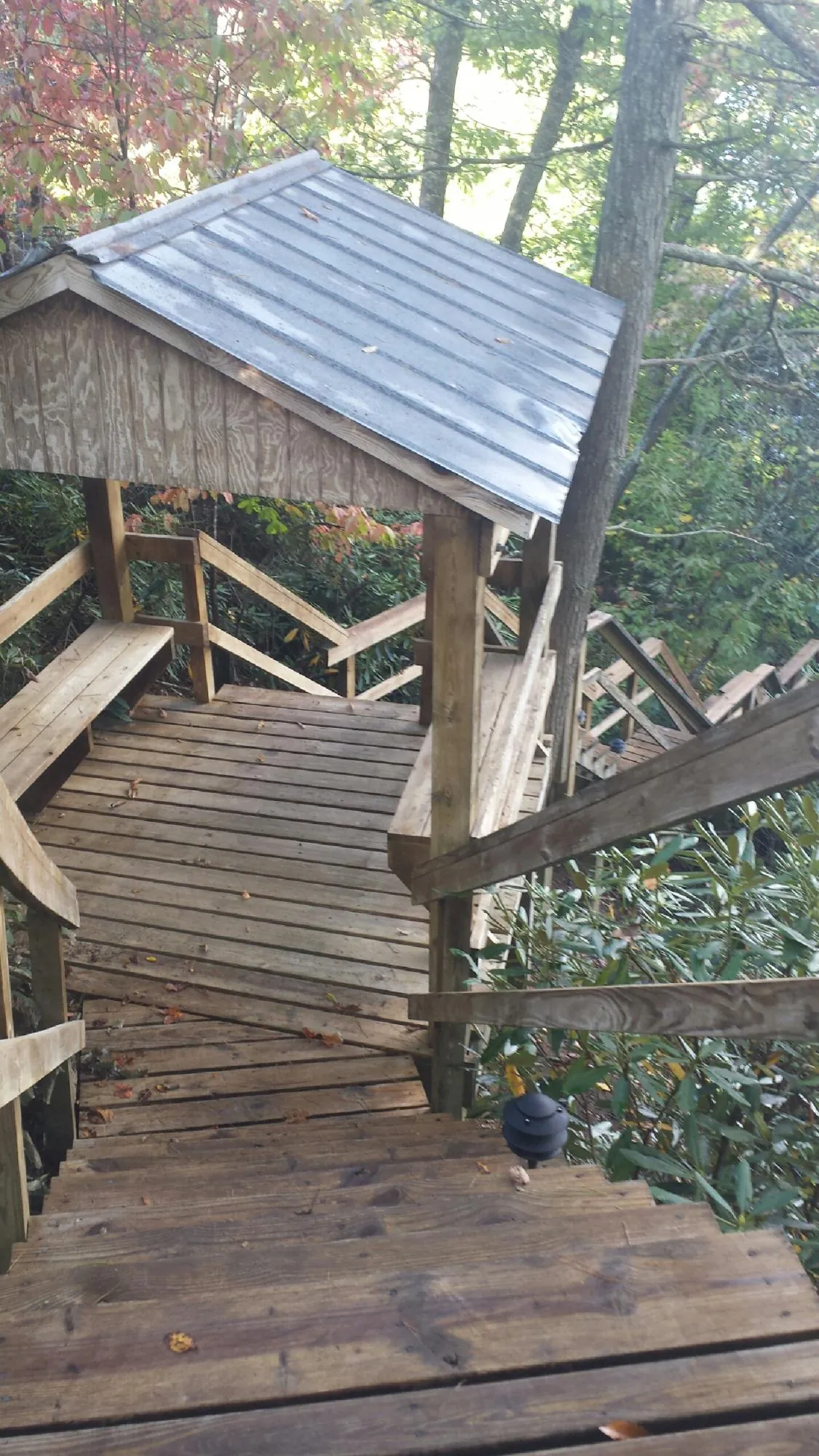 Metal roofed shelter over wooden steps on a wooded walkway — Skylight Repair & Installation work by our crew in Brentwood